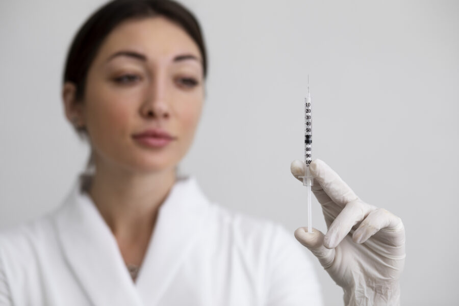 Médica con guantes sosteniendo una jeringa preparada